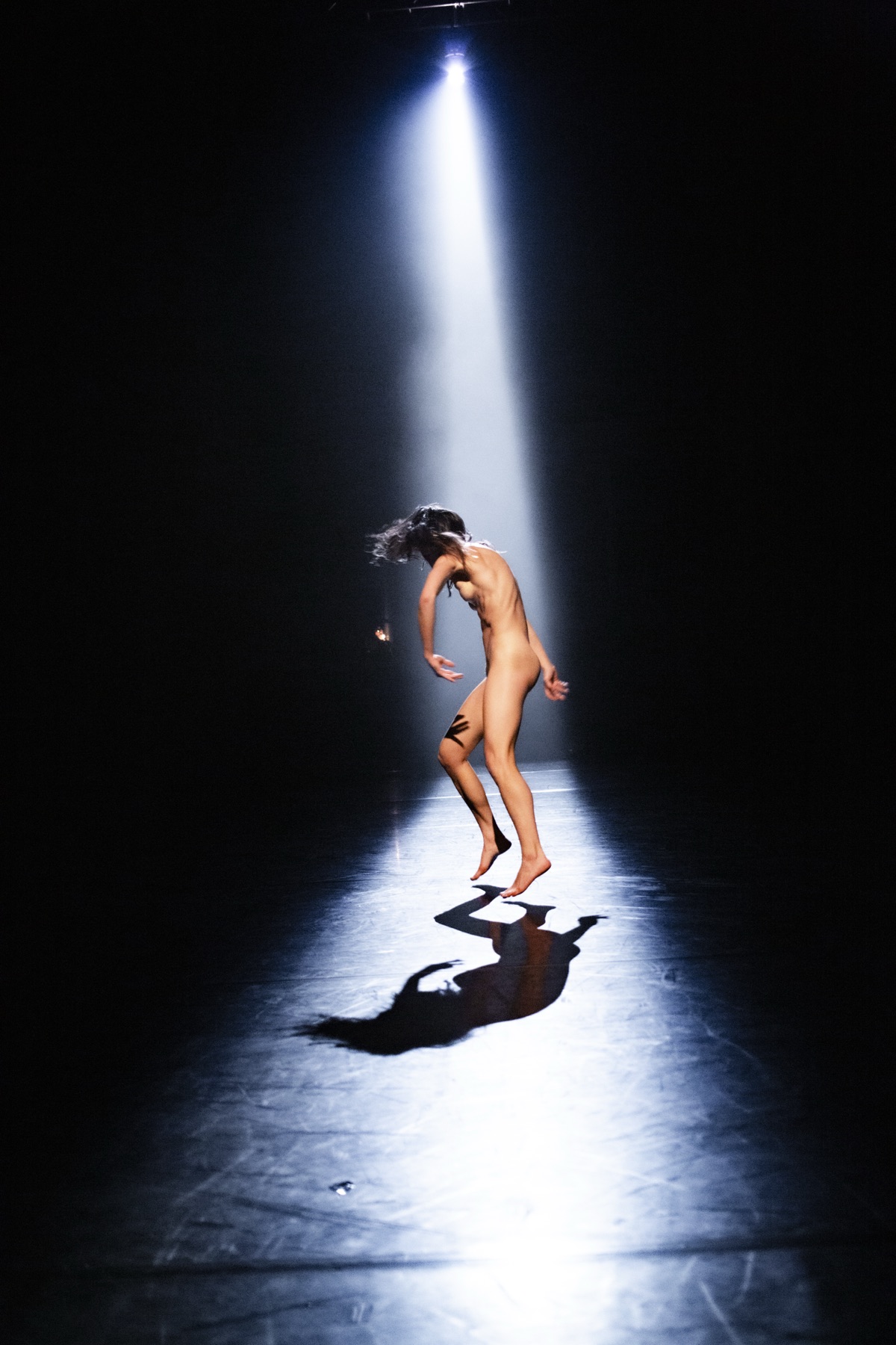 Una bailarina sola bajo un haz de luz cenital