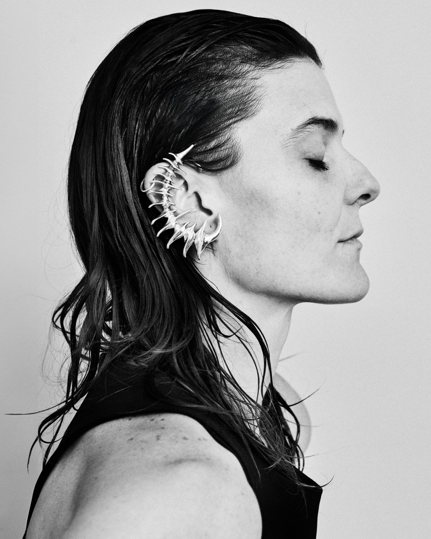 Retrato de perfil de Lucía con los ojos cerrados y un arete en forma de espina