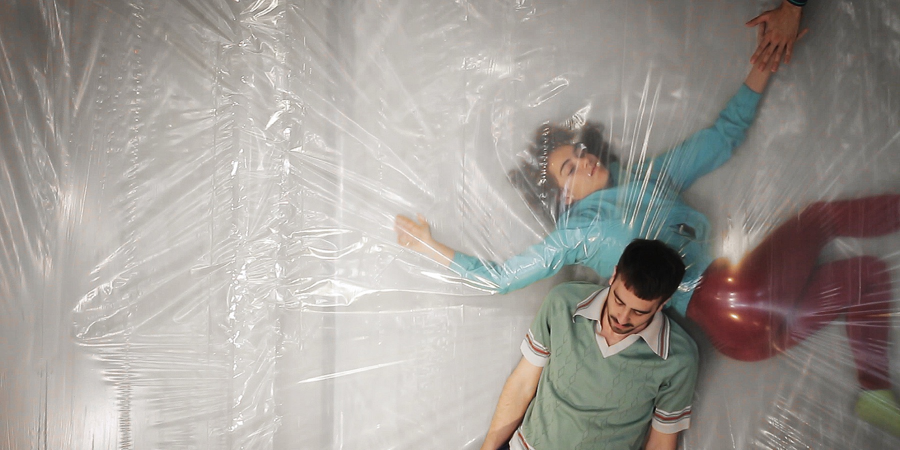 Dos intérpretes atrapados detrás de un plástico transparente